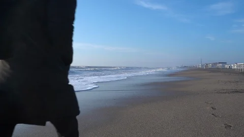 Young bearded man in black clothes is walking along the beach at the sunny day. Stock Footage 127255496