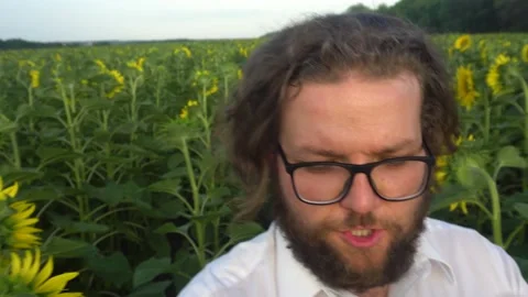 A young bearded man is broadcasting a video from a field of sunflowers.Farmer Stock-Footage 170549497