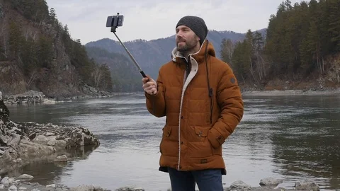 Young bearded man broadcasts online on social network outside and waves a hand 스톡 동영상 99898606