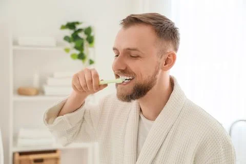 Young bearded man brushing teeth in bathroom Stock Photos