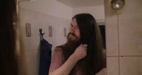 A young bearded man combing his long hair Stock Footage 87323020