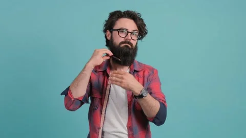 Young bearded man combing his beard looking at camera. Stock Footage 141320919