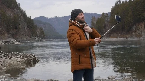 Young bearded man communicates with friends on Internet using smartphone with 스톡 동영상 99899440