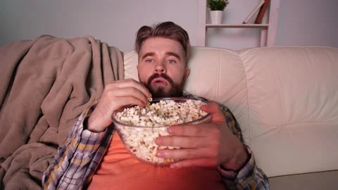 Young bearded man on cosy sofa getting bored of tv programs Stock Footage 134926317