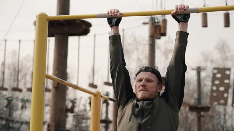 Young bearded man is doing pull ups exercises on horizontal bar during intense Stock Footage 133214138