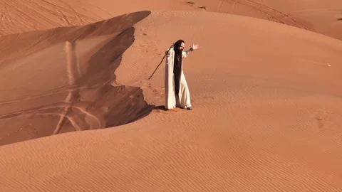 Young bearded man dressed as a shaman dancing on desert sand Stock Footage 245873671