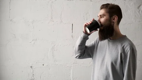 Young bearded man drink coffee looking out window. happy programmer during break Video stock 124713152