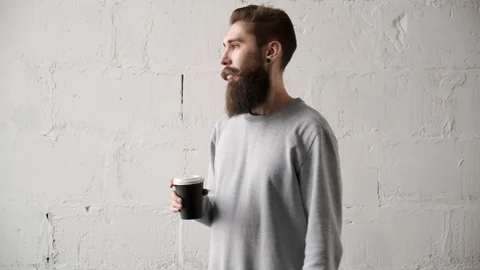 Young bearded man drink coffee looking out window. happy programmer during break Stock Footage 125120237
