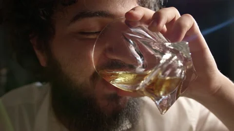 A young bearded man drinks whiskey on camera and laughs Stock Footage 223230481