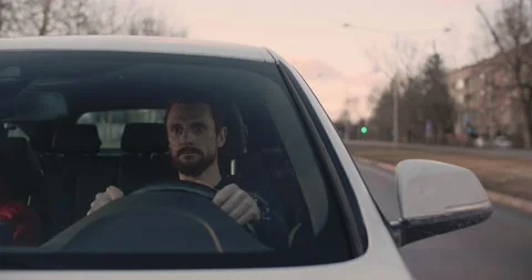 Young bearded man driving a car in the city early in the morning going to work Stock Footage 191058187