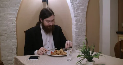A young bearded man eats at restaurant and use tablet Vidéo 88059456