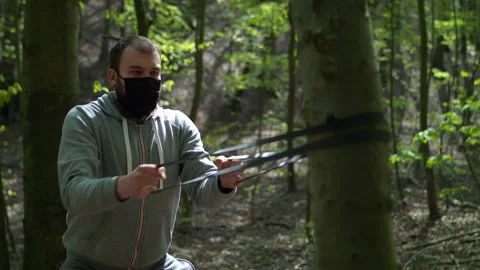 Young Bearded Man in Face Mask Exercising with Resistance Bands in Lush Forest Stock Footage 130763493