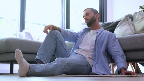 Young bearded man feeling lonely, sad and depressed, sitting on the floor of Stock Footage 344757321