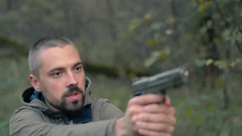 Young bearded man in the forest aims with a pistol Stock Footage 140794804