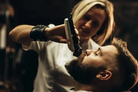 Young bearded man getting beard haircut by hairdresser Stock Photos