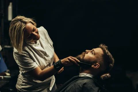Young bearded man getting beard haircut by hairdresser Stock Photos