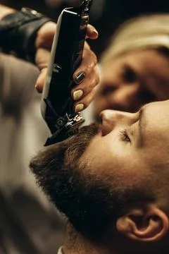 Young bearded man getting beard haircut by hairdresser Stock Photos