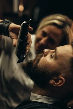 Young bearded man getting beard haircut by hairdresser Stock Photos
