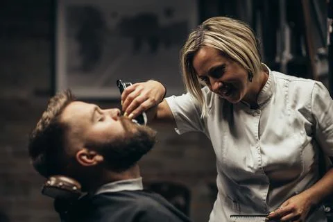 Young bearded man getting beard haircut by hairdresser Stock Photos