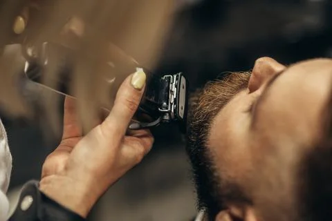 Young bearded man getting beard haircut by hairdresser Stock Photos