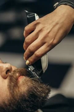 Young bearded man getting beard haircut by hairdresser Stock Photos