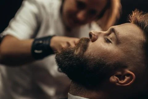 Young bearded man getting beard haircut by hairdresser Stock Photos