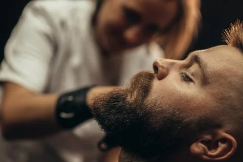 Young bearded man getting beard haircut by hairdresser Stock Photos