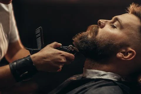 Young bearded man getting beard haircut by hairdresser Stock Photos