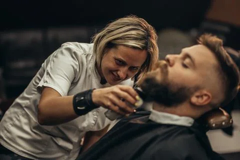 Young bearded man getting beard haircut by hairdresser Stock Photos