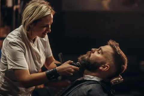 Young bearded man getting beard haircut by hairdresser Stock Photos