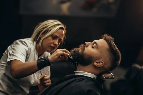 Young bearded man getting beard haircut by hairdresser Stock Photos