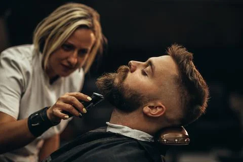 Young bearded man getting beard haircut by hairdresser Stock Photos