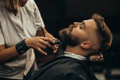 Young bearded man getting beard haircut by hairdresser Stock Photos