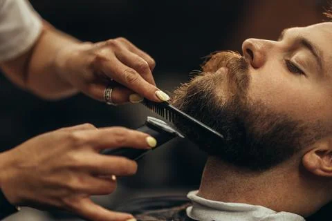 Young bearded man getting beard haircut by hairdresser Stock Photos
