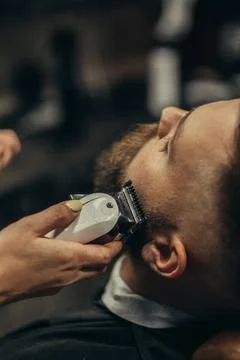 Young bearded man getting beard haircut by hairdresser Stock Photos