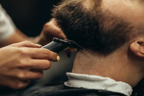 Young bearded man getting beard haircut by hairdresser Stock Photos