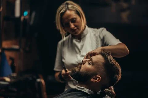 Young bearded man getting beard haircut by hairdresser Stock Photos