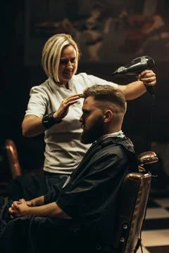 Young bearded man getting haircut by hairdresser Stock Photos