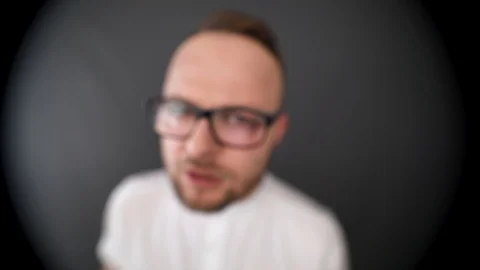 A young, bearded man with glasses looking in peephole. Looks for something  Stock Footage 90230653