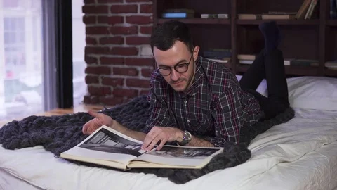Young bearded man with glasses reading the book Stock Footage 84848727