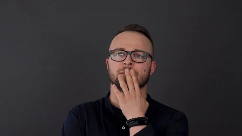 A young, bearded man with glasses. Studio shot of male thinking about something, Stock Footage 90226983