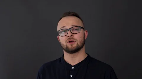 A young, bearded man with glasses. Studio shot of thoughtfully looking sideways  Stock Footage 90230187