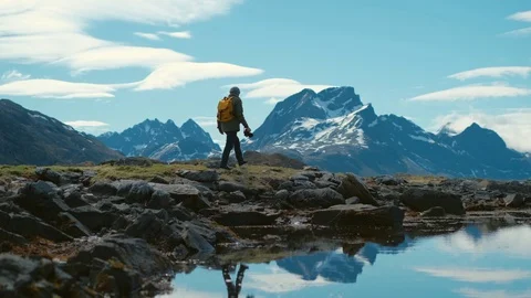 Young bearded man in a hat with a backpack comes down from the mountains on a Stock Footage 109233353