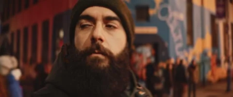 Young bearded man with a hat singing and moving his head on the street at night Stock Footage 203583406