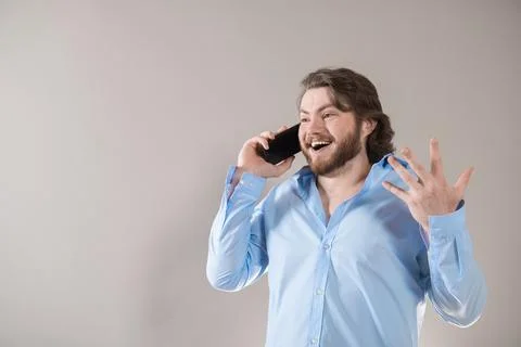 Young bearded man having call and talking on smartphone with pleasure isolate Stock Photos