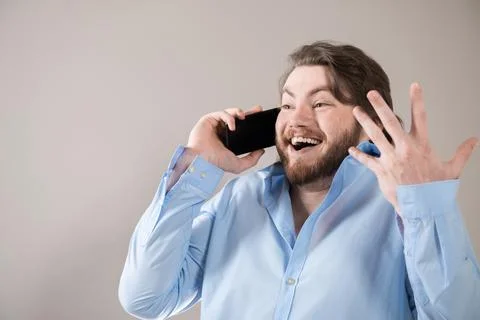 Young bearded man having call and talking on smartphone with pleasure isolate Stock Photos