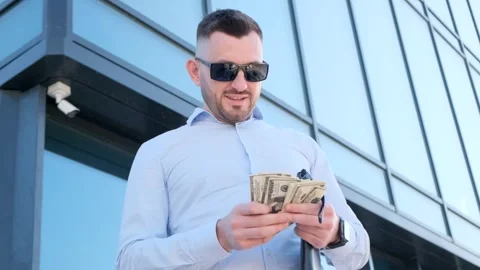 Young bearded man holding dollars cash in his hands near his office center Stock Footage 252896798