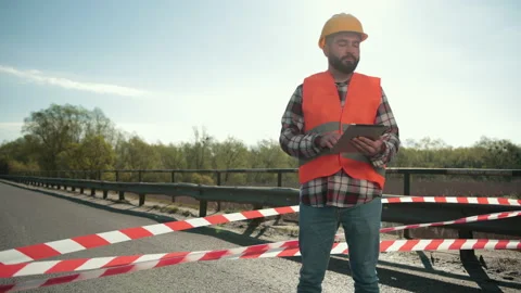 Young bearded man inspector in an orange vest and protective helmet with tablet Stock Footage 153716474