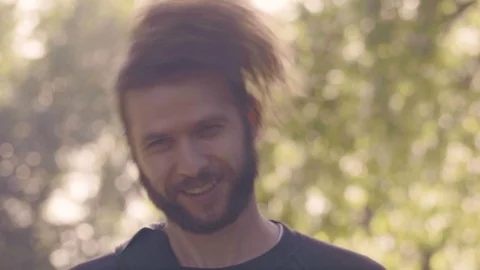 Young bearded man looking in camera and straightens disheveled hair in Video stock 99316305