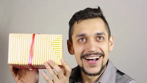 Young bearded man looking at a gift. 스톡 동영상 73719673